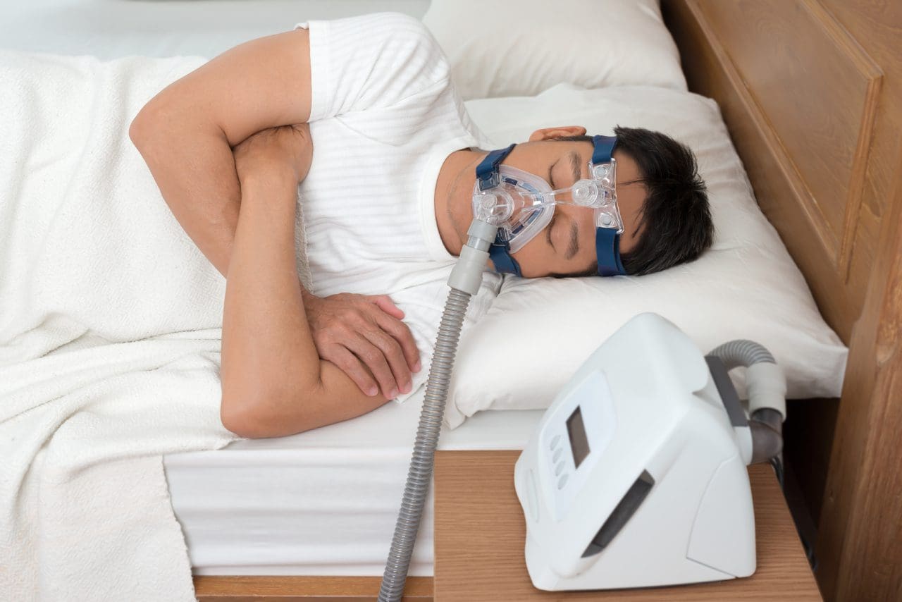 Man using sleep apnea mask in bed