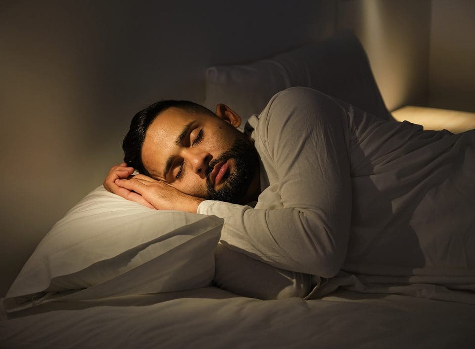 Individual asleep on white bed linens