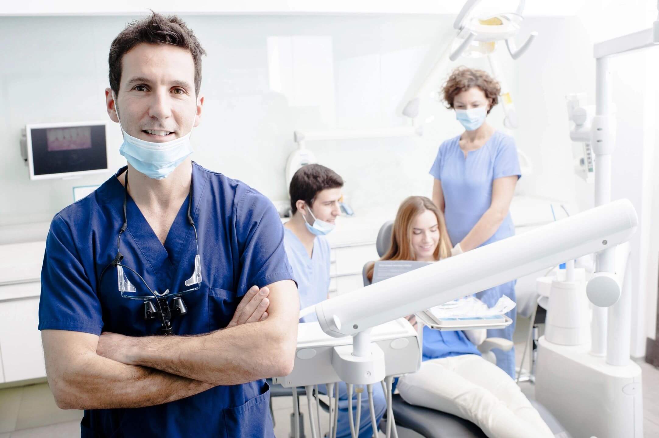 Confident dentist with team and patient in modern clinic.